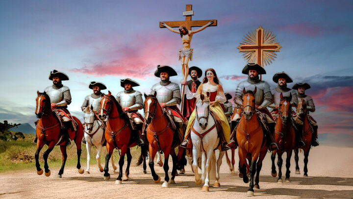 Imagen de un grupo de conquistadores españoles a caballo portando un gran crucifijo con Jesús.